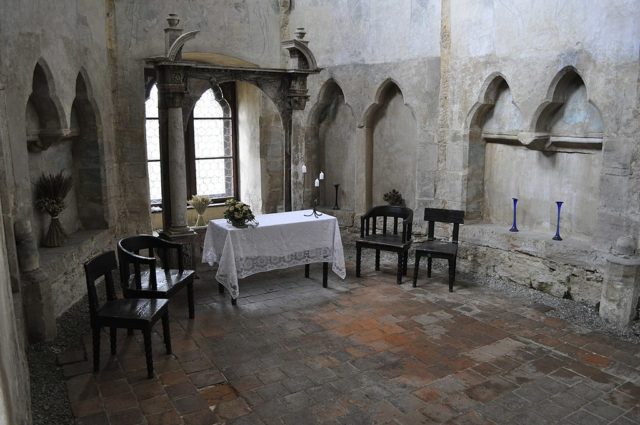 Stone chapel with chairs and a table set out. 