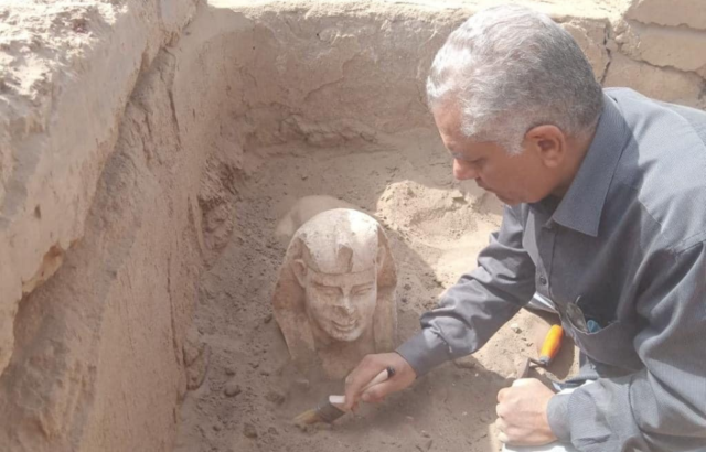 Archaeologist cleaning sand off a sphinx statue