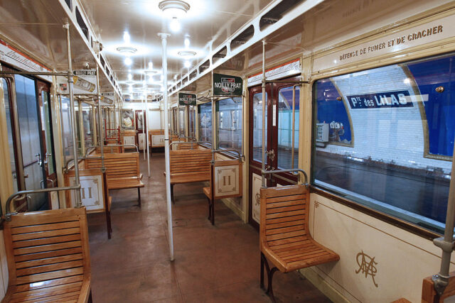 View inside a vintage Métro train with wooden bench seats. 