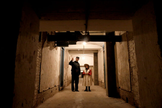 Man and a girl dressed in Civil War costumes inside an underground tunnel.