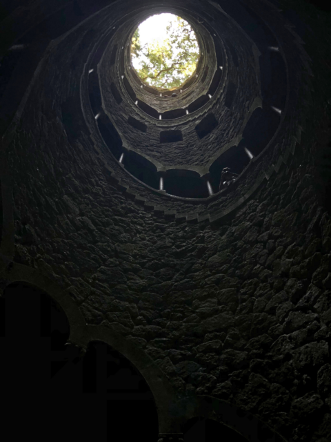 A view from the bottom of a well looking up to its opening.