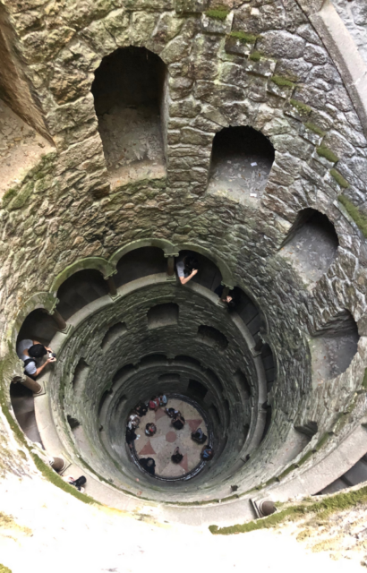 The view looking down into a well with a spiral staircase and a compass design on its floor.