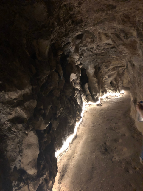 A stone tunnel with LED lighting lining the ground.