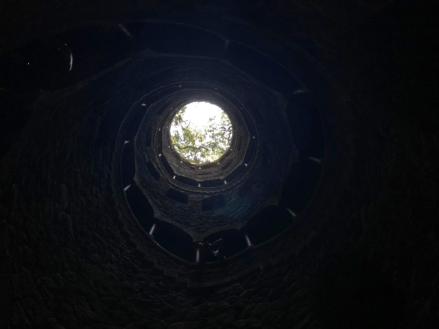 A view from the bottom of a well looking up to its opening.