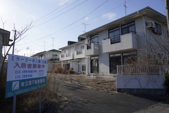 Reality sign posted outside of a row of abandoned townhouses