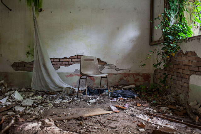 Chair in the middle of a debris-strewn room