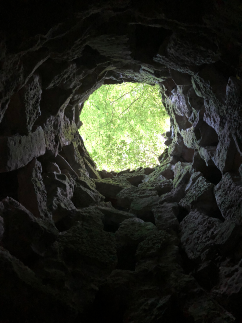 View looking up from the bottom of the Unfinished Well, the hole at the entrance showing trees.