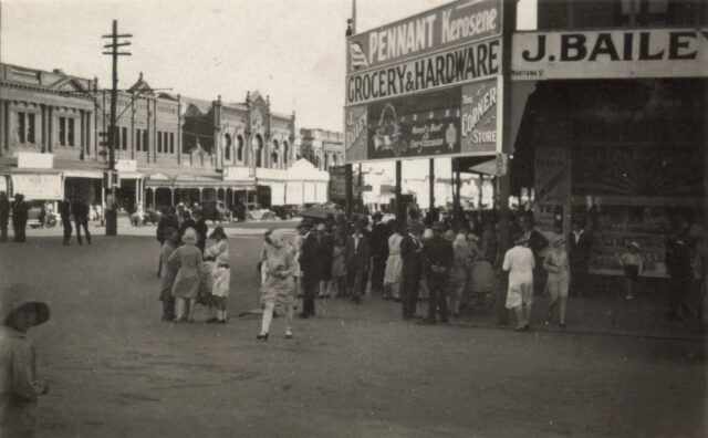 People on a city street, signs up on buildings.