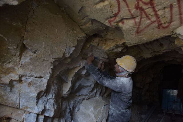 Construction worker chipping away at a rock wall