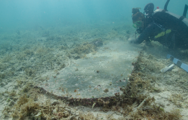 University of Miami graduate student Devon Fogarty examining John Greer's gravestone on the ocean floor