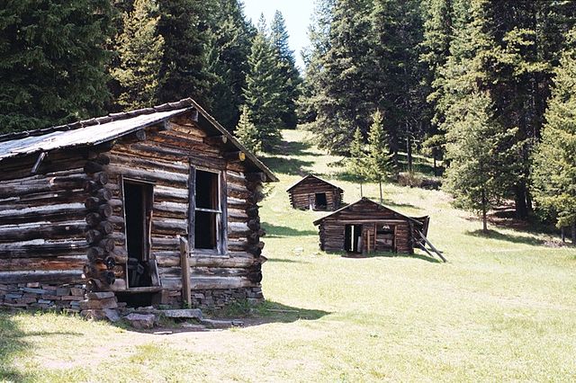 Three wooden buildings positioned near trees