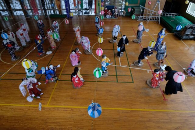 Aerial view looking down at a gym with child sized dolls placed around the room.