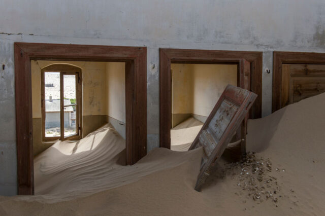 Three doors, two open, leading to rooms filled with large piles of sand.