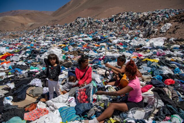 Women and children sifting through the "fast fashion" mountain