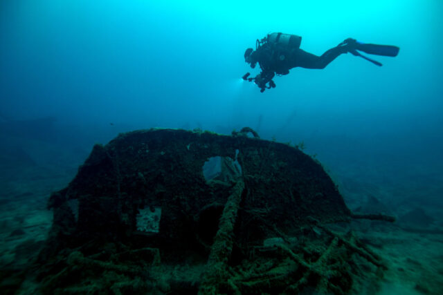 Diver swimming above shipwreck.