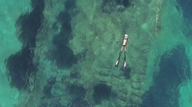 Aerial view of diver swimming over a shipwreck.