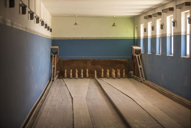 Blue room with two wooden bowling lanes in the middle.