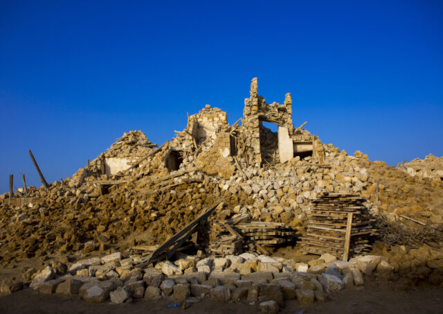 The ruins of a building on a hill of rubble.