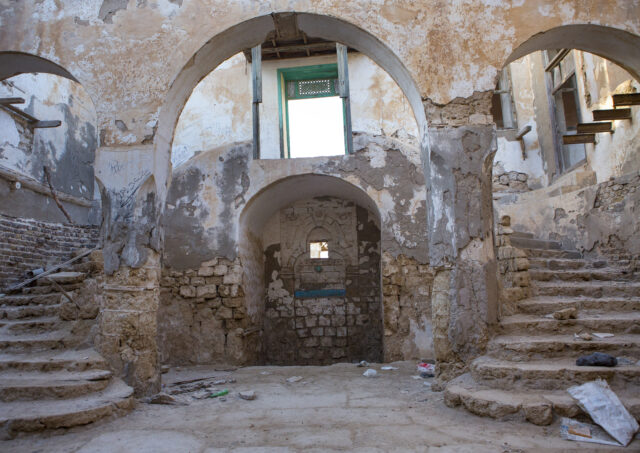 The inside of a decaying building, a window near the roof.