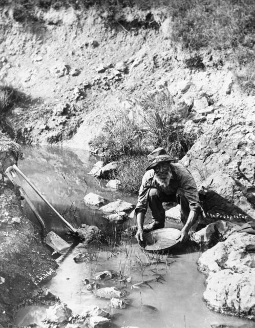 A man panning for gold in a riverbed.