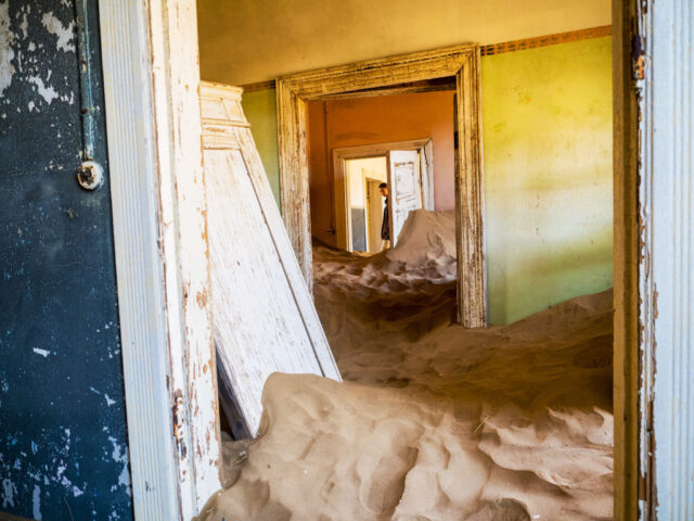 Abandoned house with many open doors, full of sand.