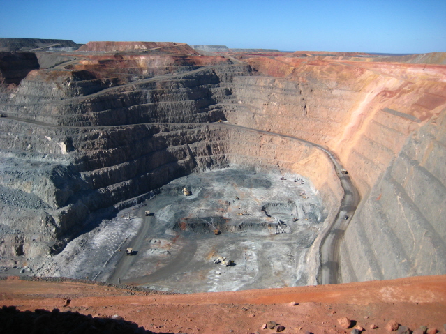 The walls of the Kalgoorlie Super Pit, vehicles inside. 