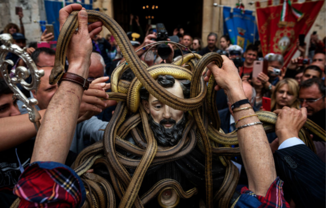 Group of people placing live snakes on the statue of Saint Domenico di Sora