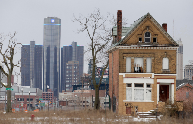 Two sides to Detroit. In the foreground, an old, rundown house, and in the background, General Motors (GM) headquarters.