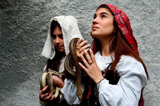 Two women holding live snakes