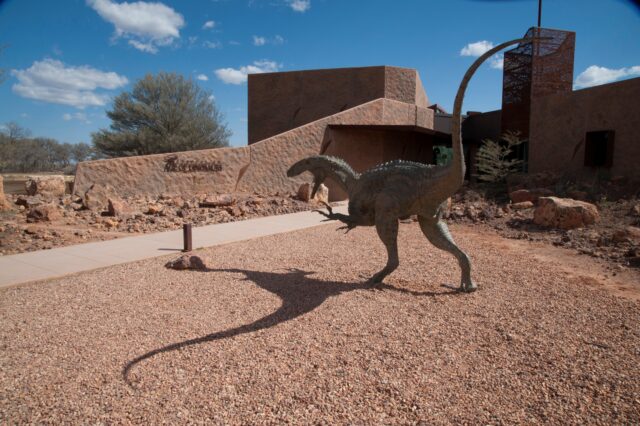 A dinosaur statue in front of a museum.