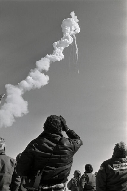 Onlookers watch as the Challenger Space Shuttle explodes in the sky. 