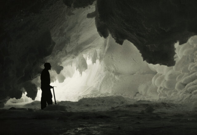 The shadow of a man with an ice pick inside an ice cavern.
