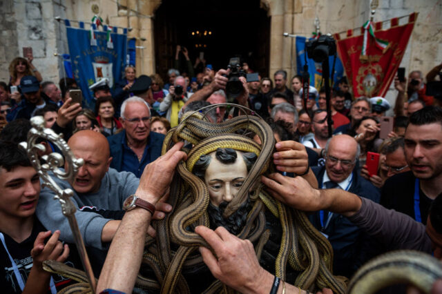 Large crowd gathered around a statue of Saint Domenico di Sora, which is covered in live snakes