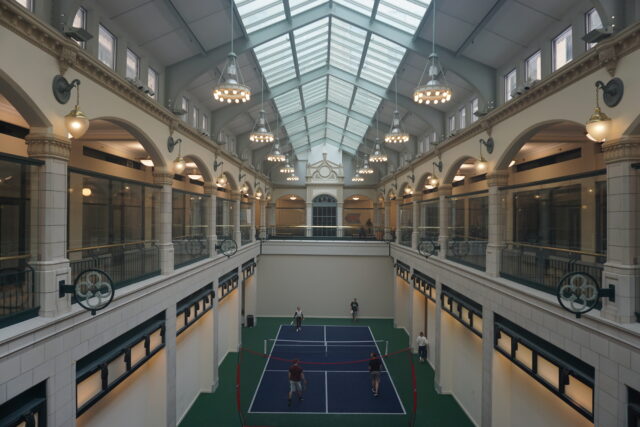 Second-floor view of a pickleball court with four people playing.
