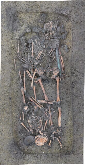 Aerial view of multiple skeletons in a burial site in the ground.