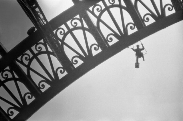 Man hanging from the Eiffel Tower to paint it.