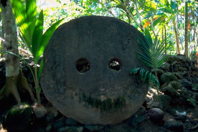 Tall circular stone with two small holes cut in the center.