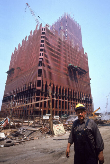 Construction worker in a hard hat standing in front of a half built tower.