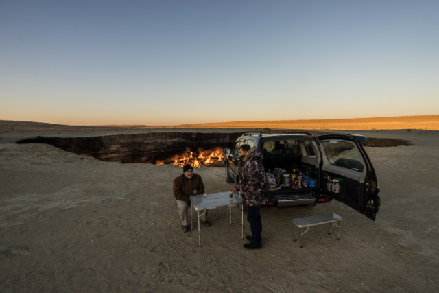 Two men standing near a car that's parked near the Gates of Hell