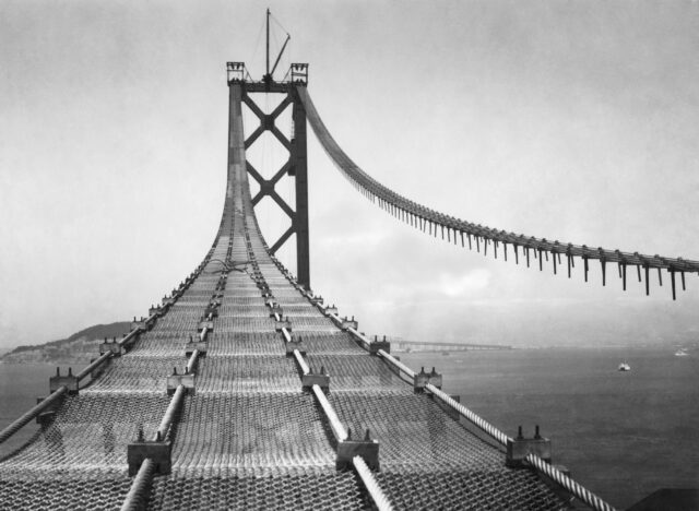 View of the chains and cables of the Golden Gate Bridge as well as a tower.