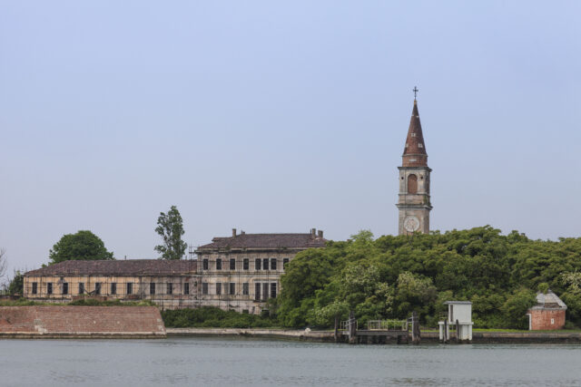 View of a hospital and its tower on the coast of a shoreline.