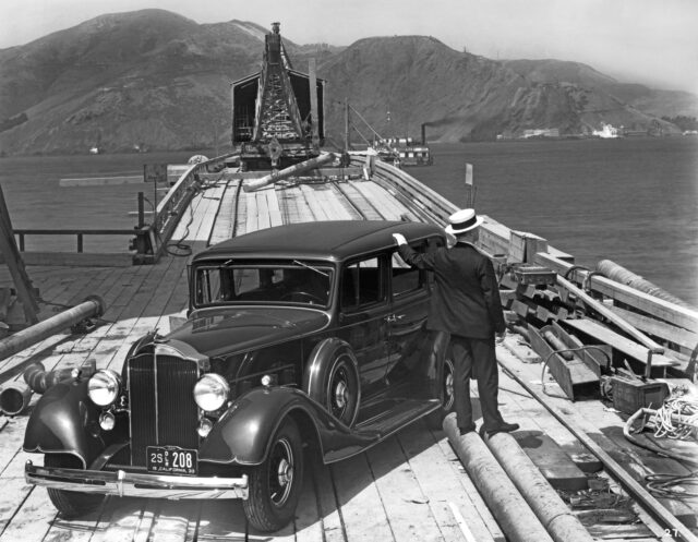 A man stands by a car at a construction site for the building of the Golden Gate Bridge.