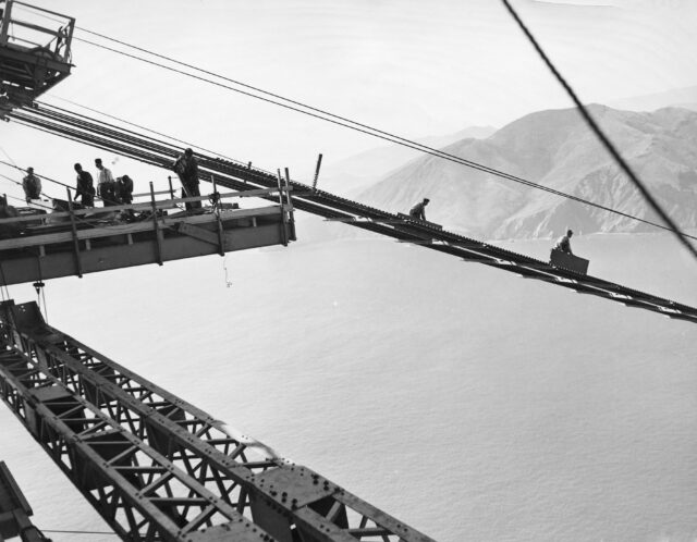 Construction workers building the catwalk of the Golden Gate Bridge.