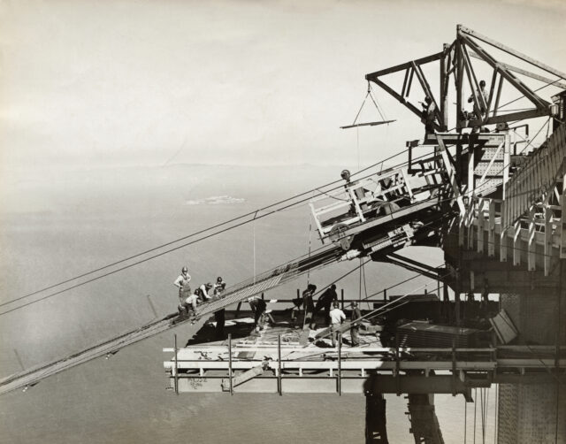 Construction workers working on the catwalk of the Golden Gate Bridge.