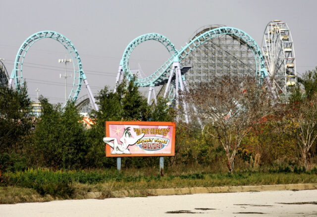 A sign for Six Flags Amusement Park flanked by the frame of a roller coaster ride.