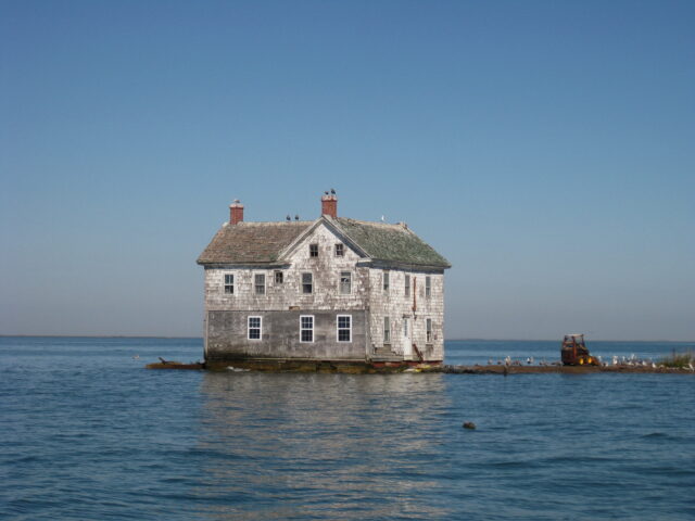 A decrepit house surrounded by water.