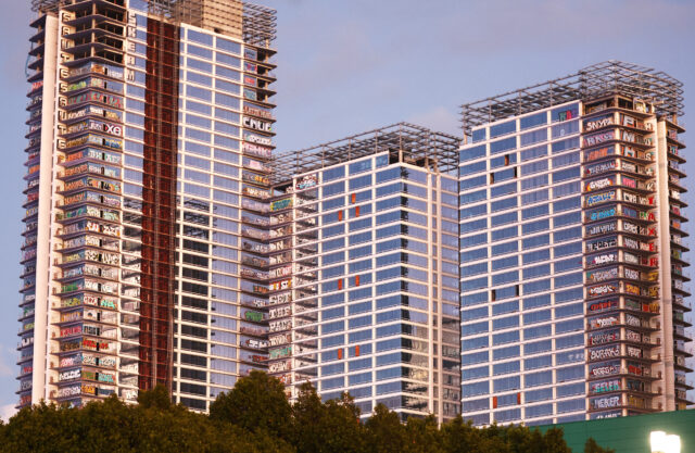 Three skyscrapers with graffiti on their windows.