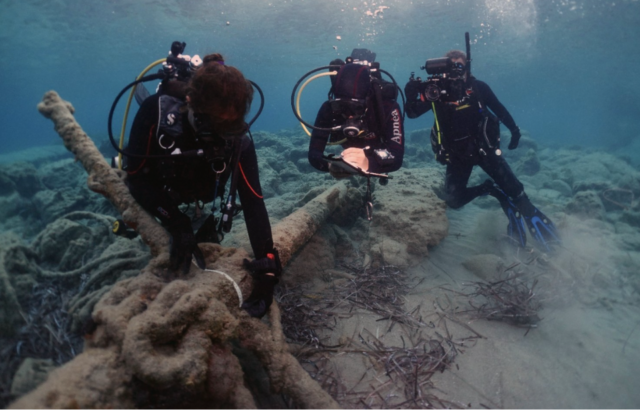 Three divers examine an anchor.