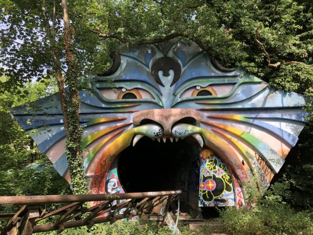 Cat-themed wall with a rusty rollercoaster rail going through its mouth at Spreepark