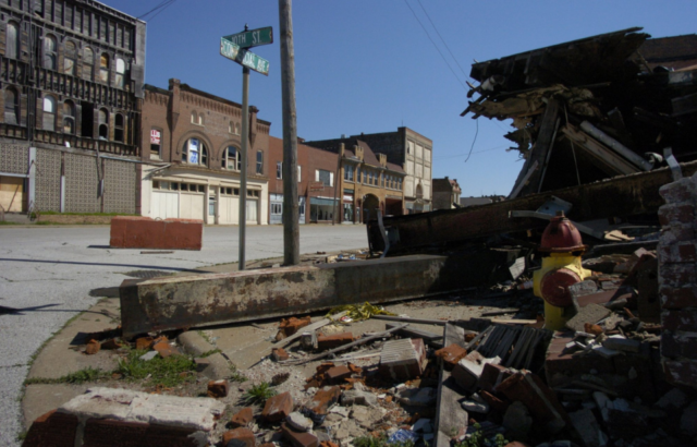 An abandoned strip of buildings, a destroyed building in front of them.